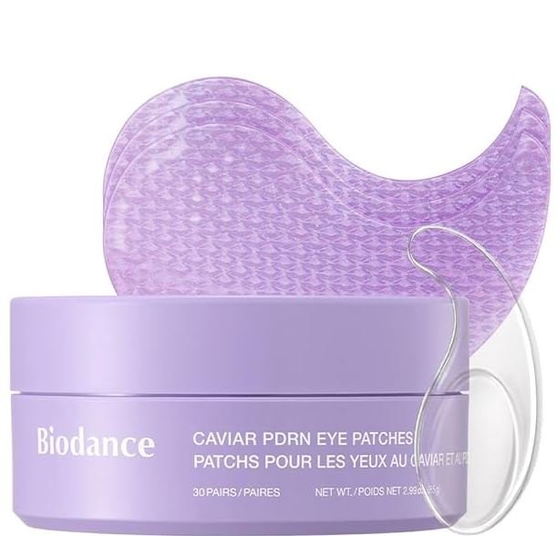 A light purple jar of Biodance Caviar PDRN Eye Patches shown with several purple textured hydrogel patches visible behind it. A small transparent applicator spatula is positioned on the right side of the jar. The packaging text highlights the caviar and PDRN active ingredients.